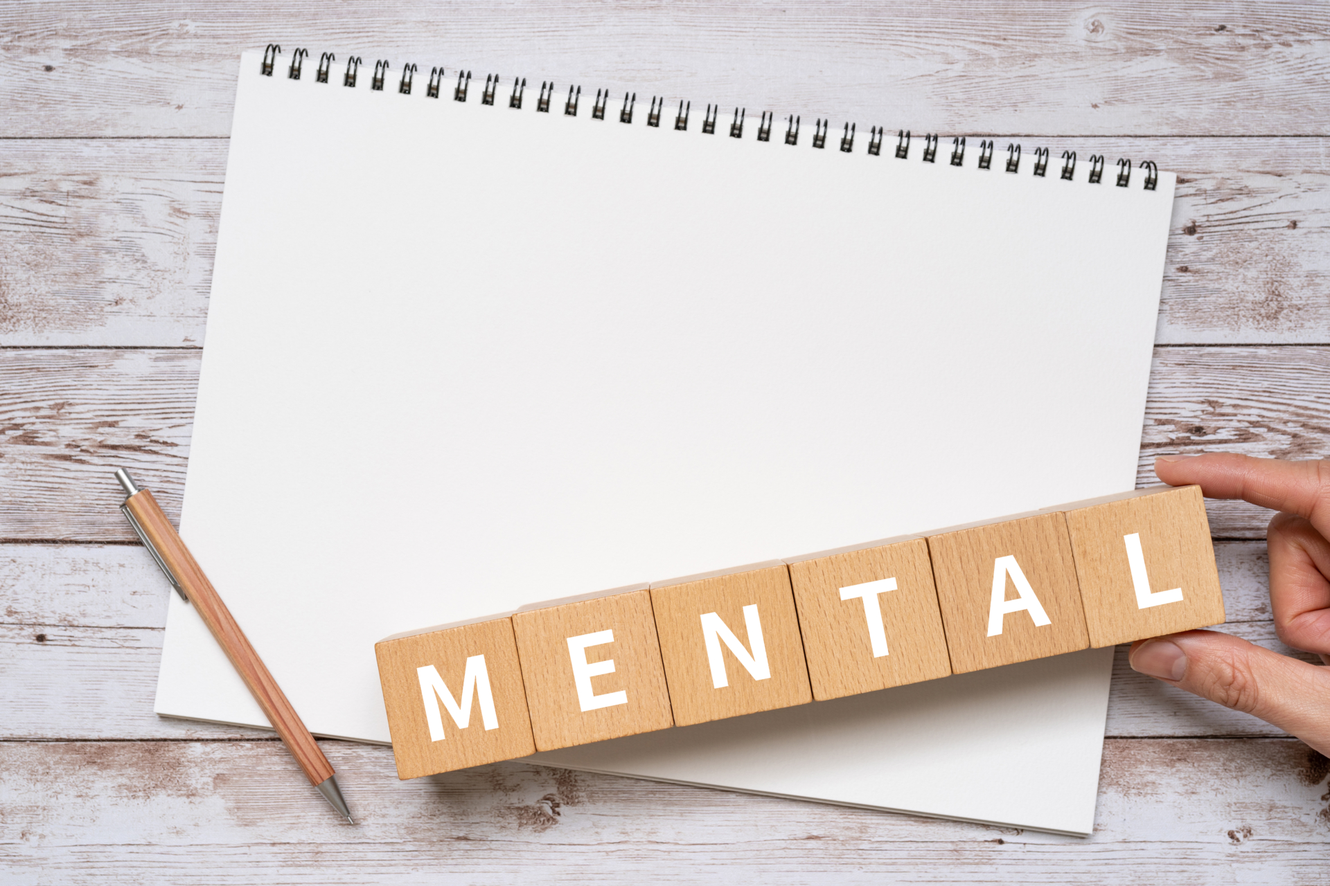 白紙のノートにMENTAL(メンタル)と書いてある積み木がのったイメージ画像